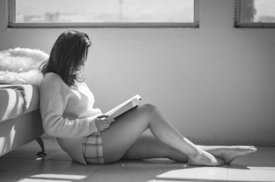 Brazilian woman reading a book quietly by a window